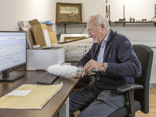 Man achter laptop: stoft zijn toetsenbord af met een plumeau
