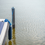 Boot met zeil ligt vast met touw aan houten paal