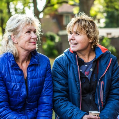 Twee vrouwen zitten in tuin en praten met elkaar