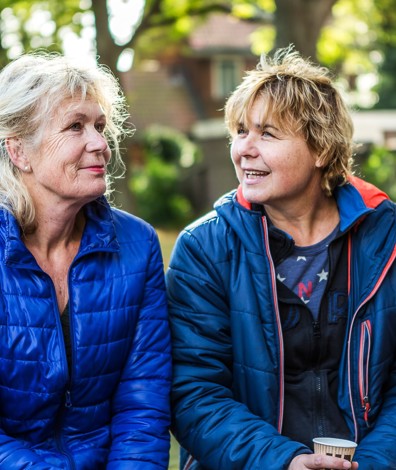 Twee vrouwen zitten in tuin en praten met elkaar