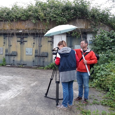 man en vrouw staan met camera voor munitiebunkers te filmen