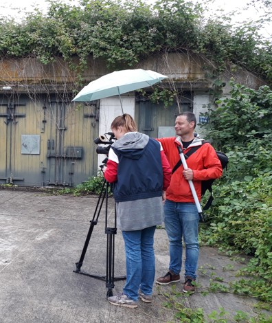 man en vrouw staan met camera voor munitiebunkers te filmen