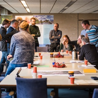 Groep mensen staat om tafel heen