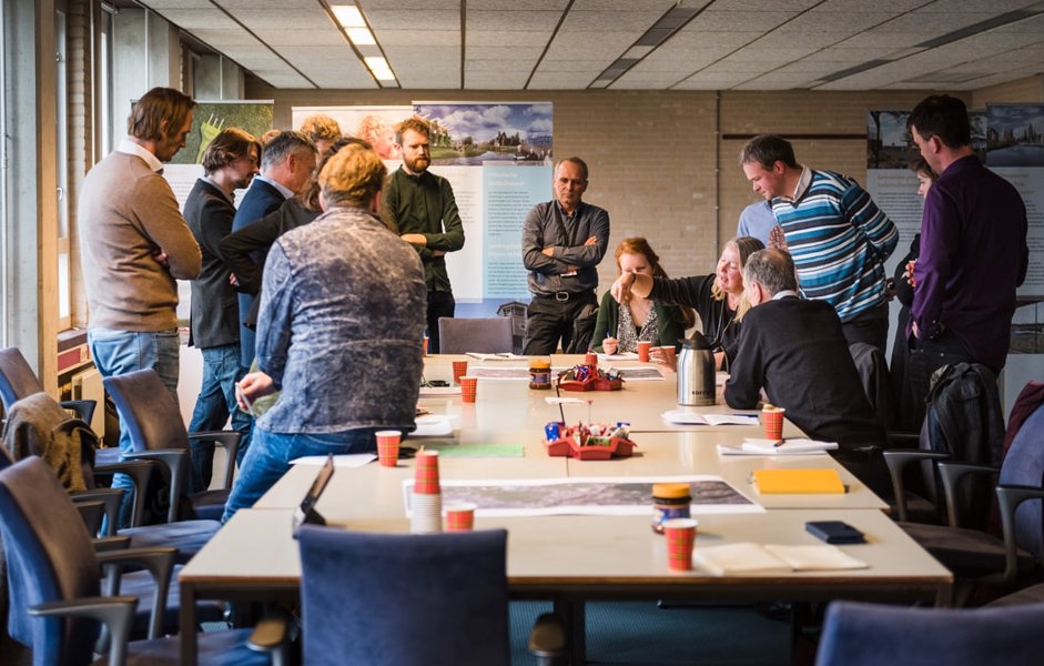 Groep mensen staat om tafel heen