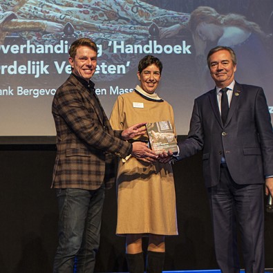 Evelien Masselink en Frank Bergevoet reiken het eerste exemplaar van Handboek Ordelijk Vergeten uit aan gedeputeerde Meindert Stolk. Foto: Floris Scheplitz