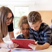 Kinderen kijken met leraar in de klas op tablet