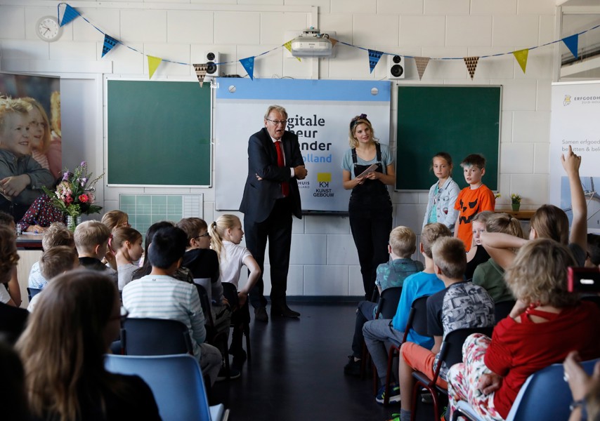 Man en vrouw staan voor klas waar leerlingen zitten