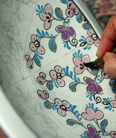 Plateelschilderen: ongeglazuurd wit aardewerk wordt versierd door een plateelschilder met bloemen..