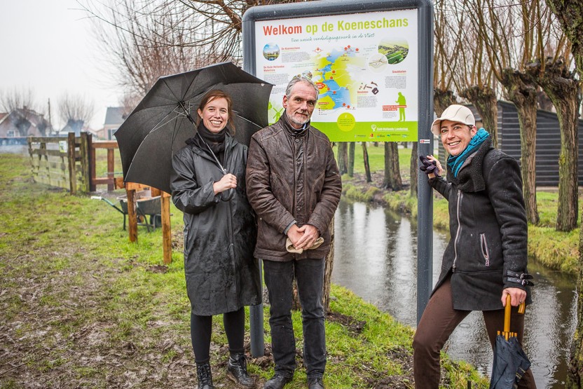 Twee vrouwen en een man staan voor een informatiebord