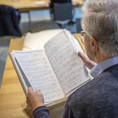 Man kijkt naar oude bron en heeft computer naast zich om het in te voeren.