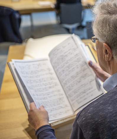 Man kijkt naar oude bron en heeft computer naast zich om het in te voeren.