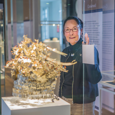 Vrouw met bril bekijkt collectie Zilvermuseum in glazen vitrine