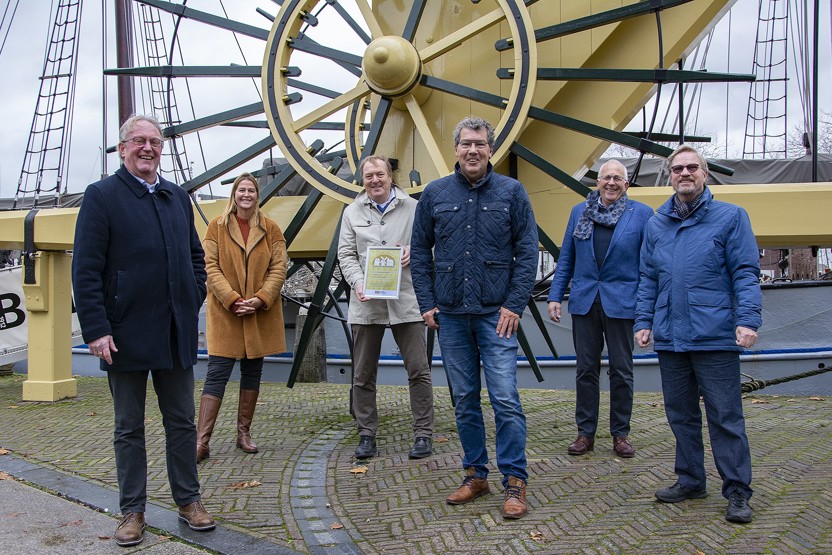 5 mannen en een vrouw staan voor de stadskraan