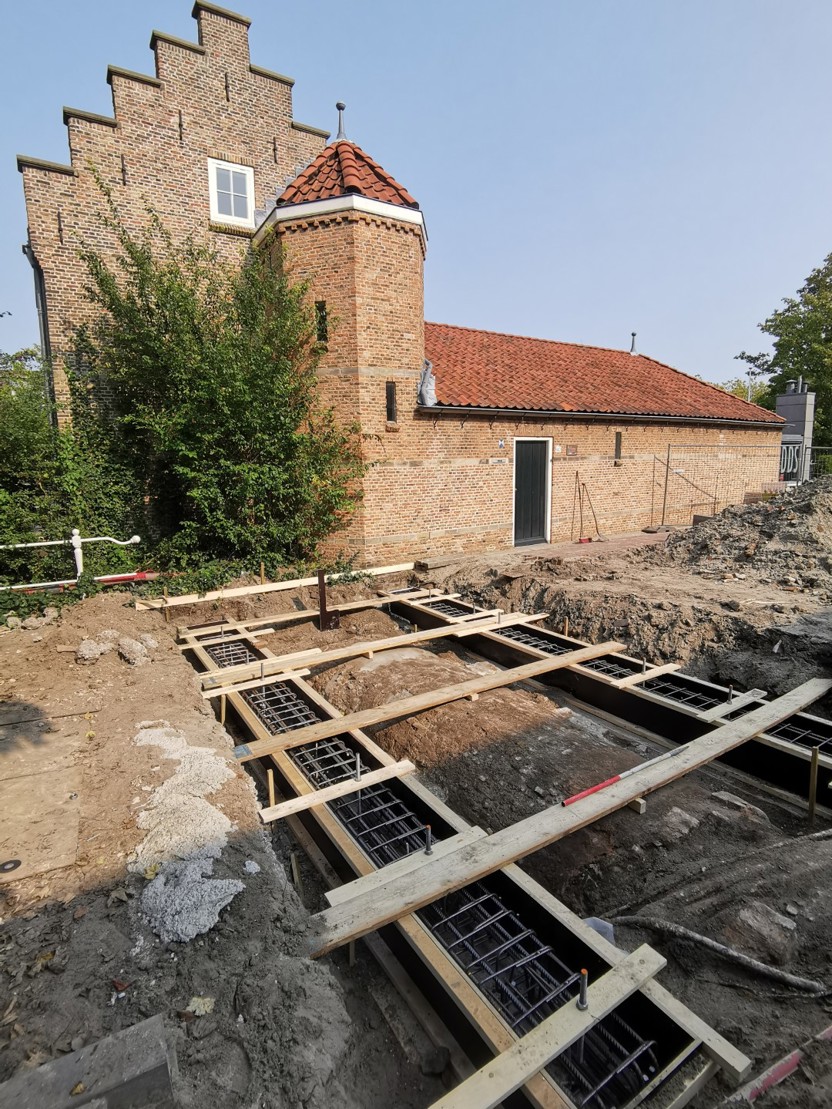 Archeologische put naast een oud bakstenen gebouw