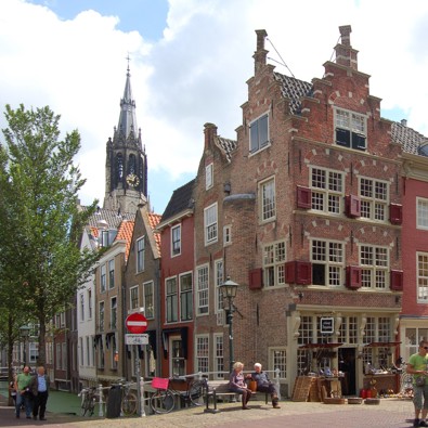 Mensen lopen op Oude Delft in Delft met op de achtergrond de Nieuwe Kerk