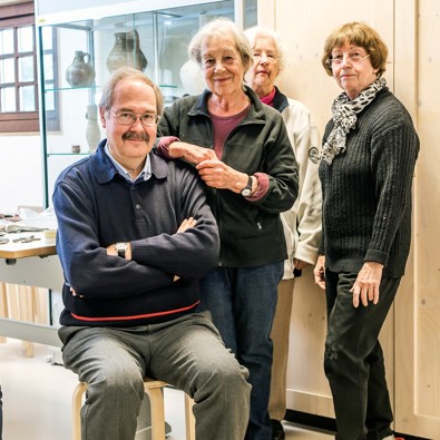 Twee mensen zitten op krukken en drie mensen staan in ruimte