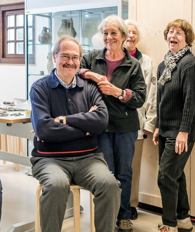 Twee mensen zitten op krukken en drie mensen staan in ruimte