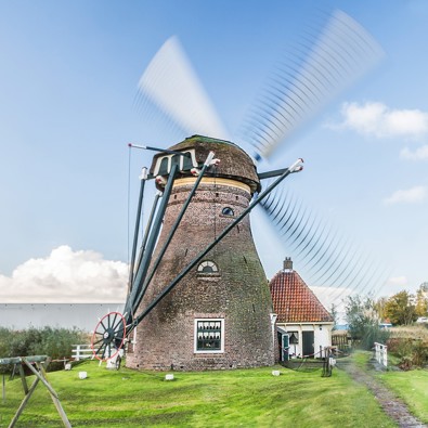 Stadsmolen in Leiden met wit molenaarshuisje en water ernaast