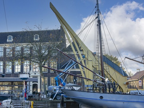 Herenhuis aan kade met zeilboot in het water